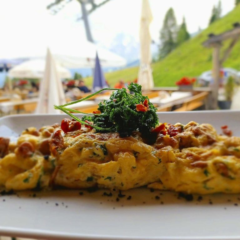Leckere Omelette mit Kräutern und Pfifferlingen, serviert in einer Berglandschaft.