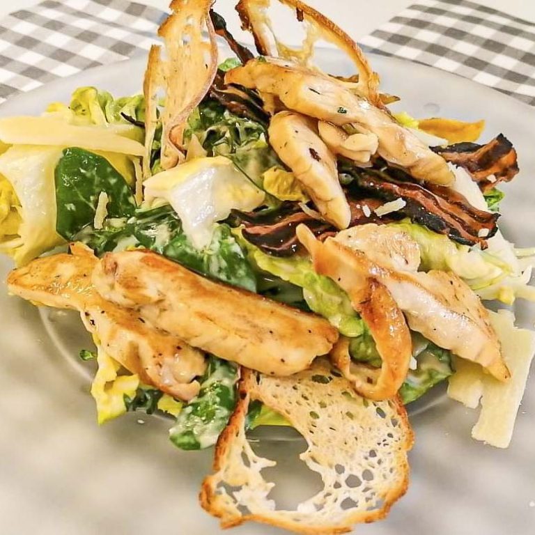 Salat mit gegrilltem Hähnchen, grünem Blattgemüse und knusprigen Käseflocken.