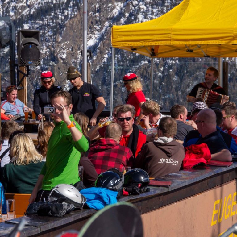 Skifahrer und Feiernde auf einer Berghütte mit Live-Musik und alpenländlicher Atmosphäre.